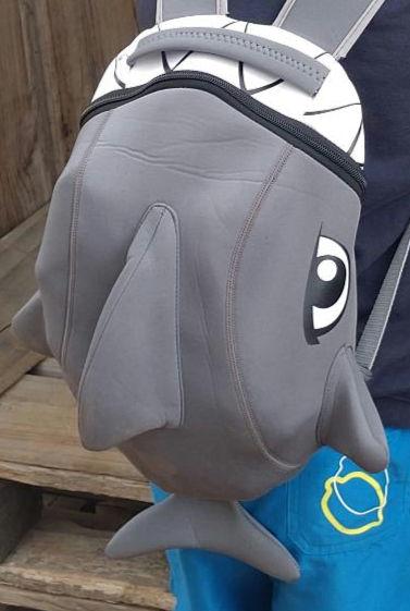 Ein grauer Hairucksack, rechts ist ein Comic-artiges Auge
